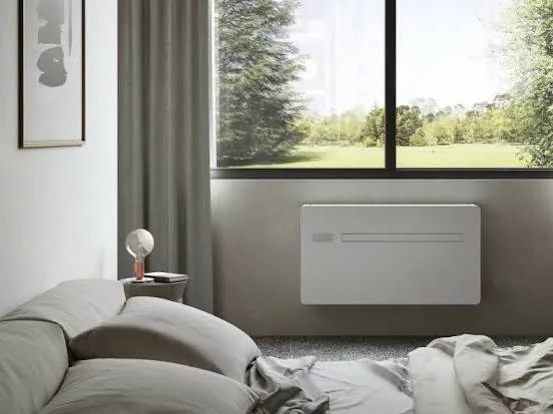 Schlafzimmer mit weißem Monoblock-Klimagerät an der Außenwand unter dem Fenster